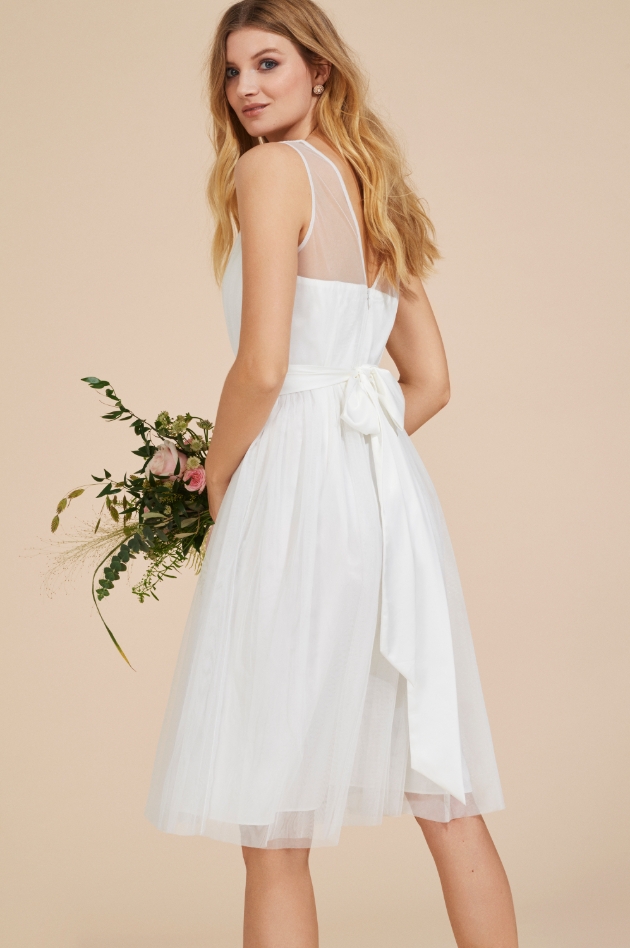 Model is in studio and wearing a white tulle knee-length style