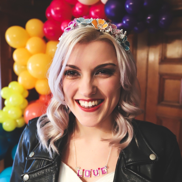 Bride wearing leather jacket and colourful jewellery in front of a balloon arch.