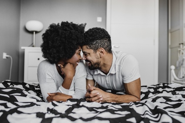 couple laying on a bed looking at eachother