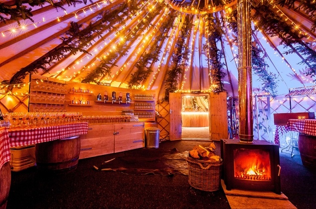 Interior of wedding yurt in winter with log burner, fairy lights and bar.