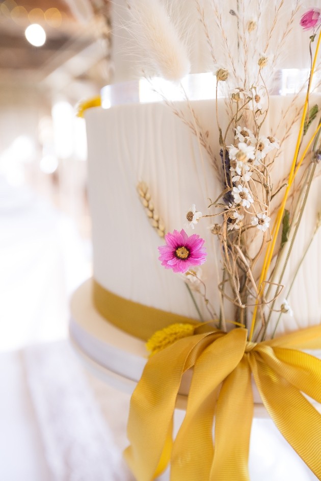 Cream wedding cake with pops of yellow and dried flowers