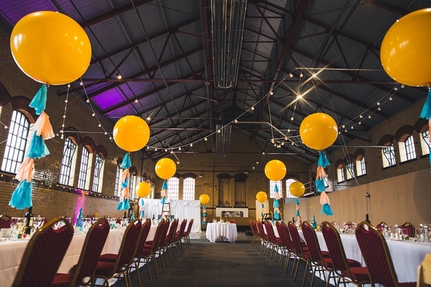 Room dressed for a wedding party with brightly coloured balloons and tassels