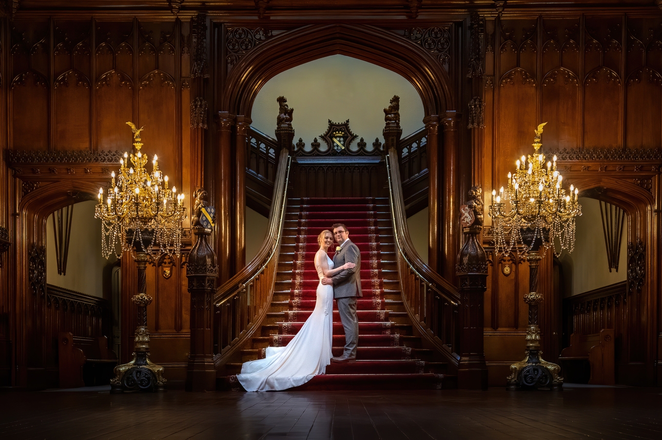 Newlywed couple on grand staircase with chandleiers by Lisa Kershaw of Drawn by Light Photography