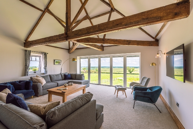 lounge area with blue and grey sofas exposed beams and country views