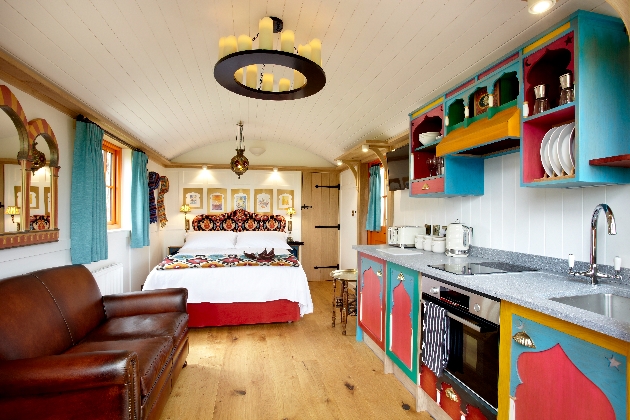 Interior of hut with leather sofa and brightly painted kitchen suite