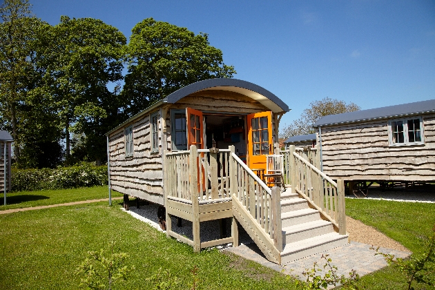 wooden shepherd hut on the grass with trees in the background