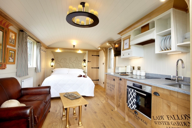 inside shepherd hut which has a leather sofa, wooden kitchenette, and Egyptians inspire decor