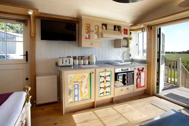 kitchenette inside shepherds hut with drawn images on the cupboard