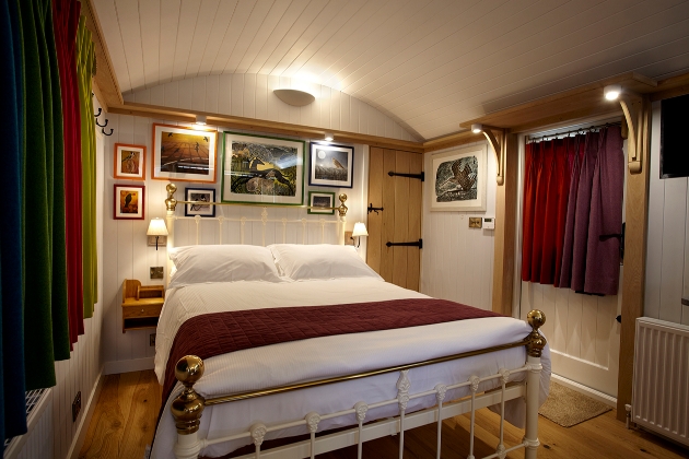 bedroom with coloured curtains closed and lamps lite and bed in the centre