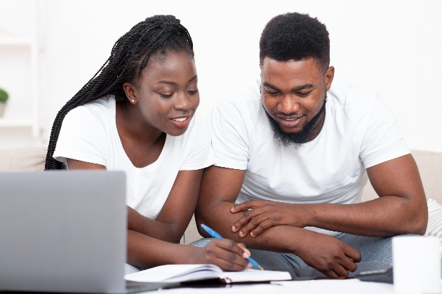 couple sitting on sofa with laptop