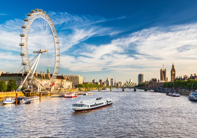 The London Eye, next to River Thames with boats on it sunny day 