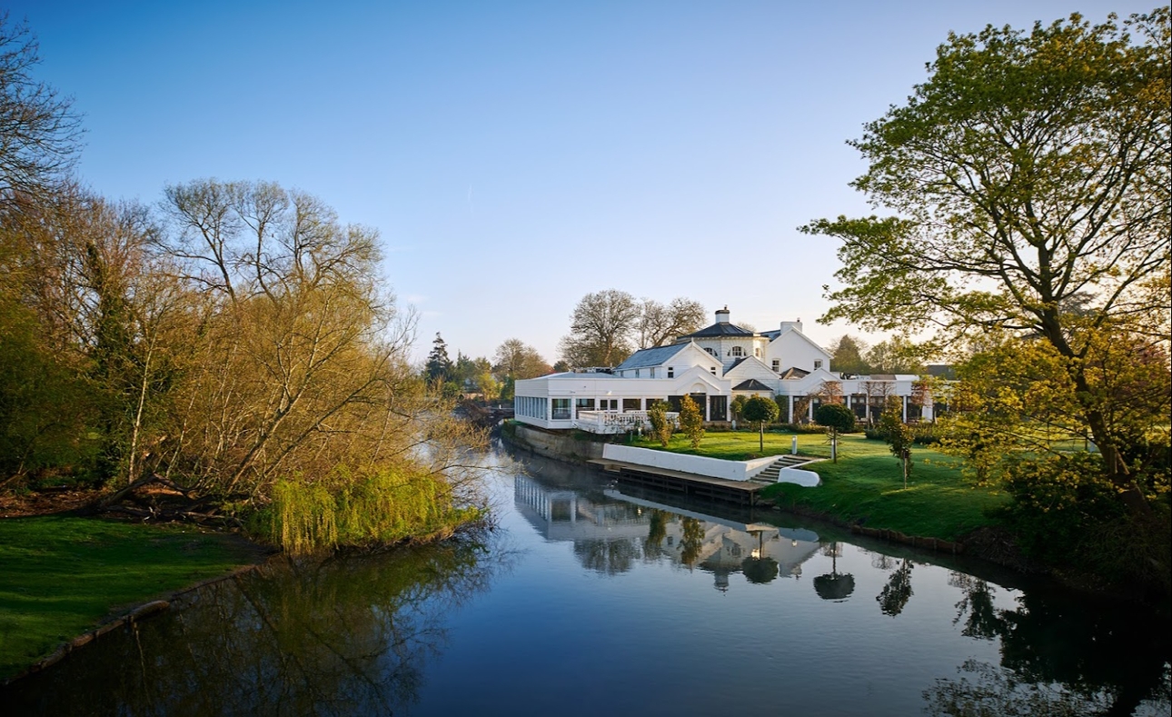 white building on island surrounded by water and tress sunny blue day