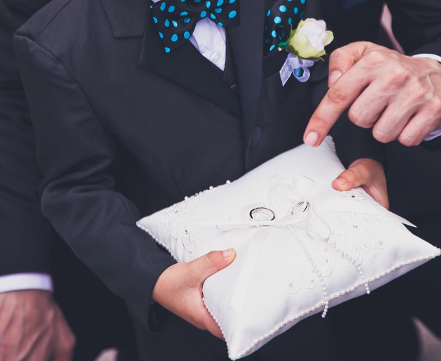 boy in a suit holding a ring pillow