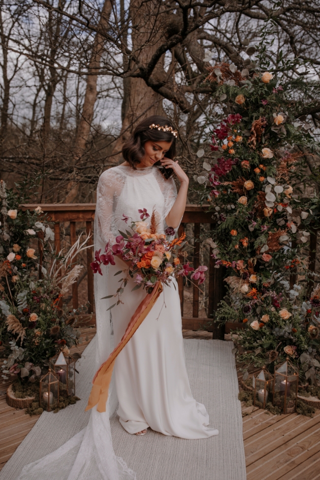 bride in front of floral wild flower arch