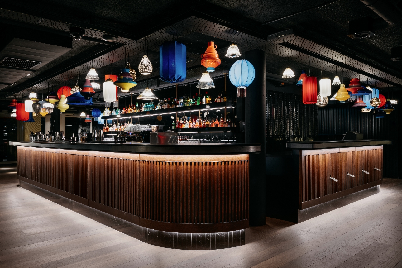 dark room with curved bar with coloured lanterns