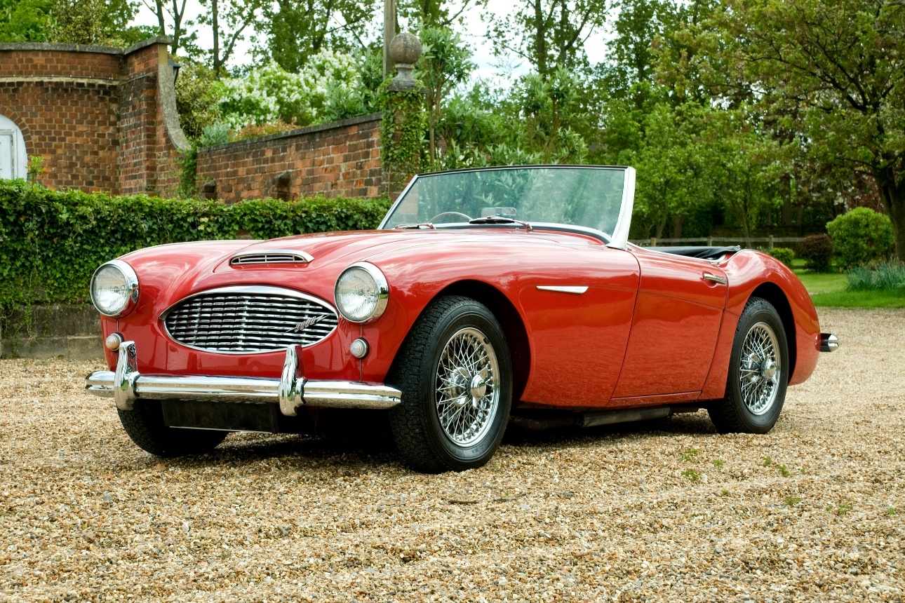 red classic car on a pebble driveway