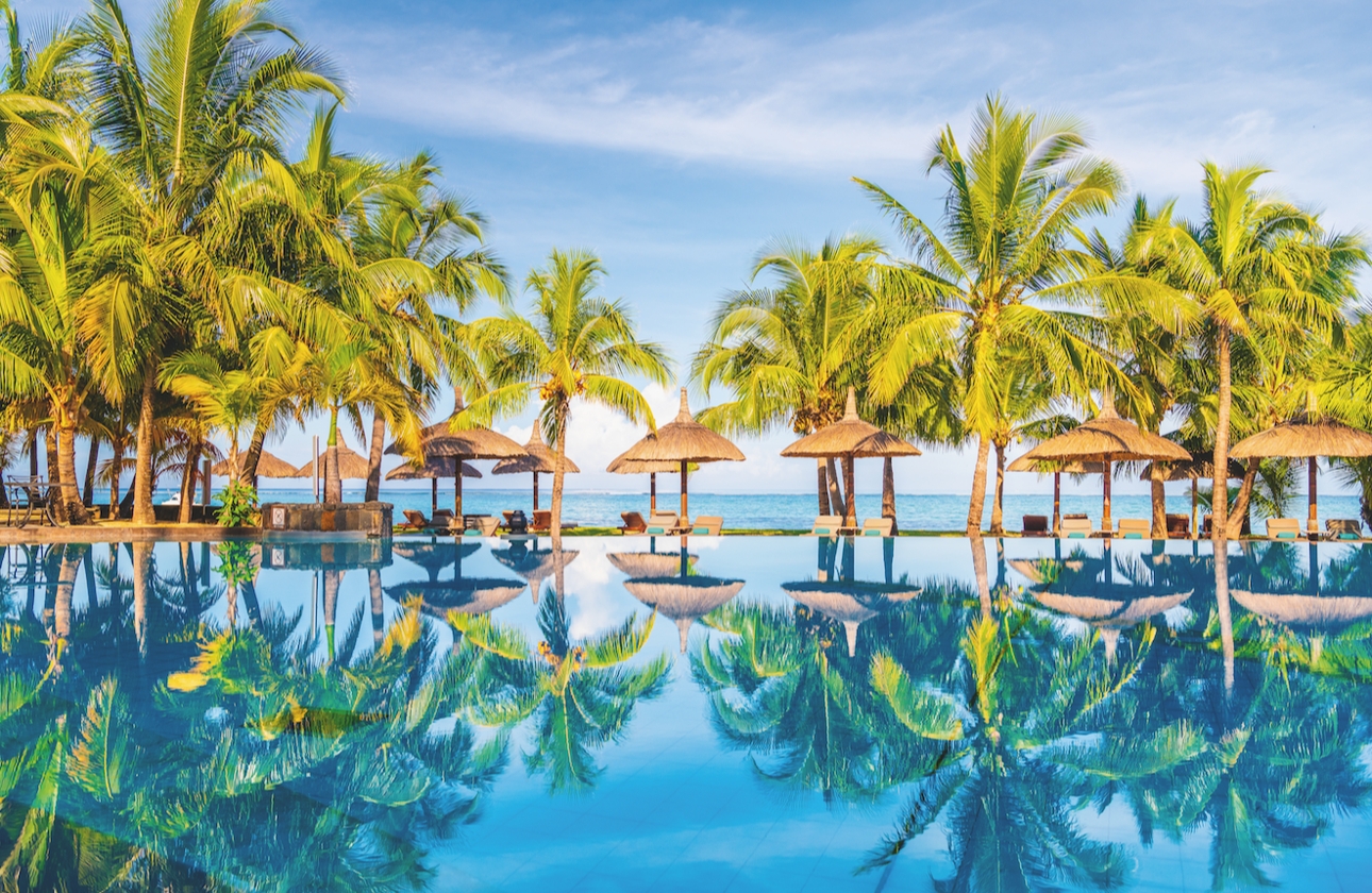 infinity pool with reflections of the blue skies and palm trees