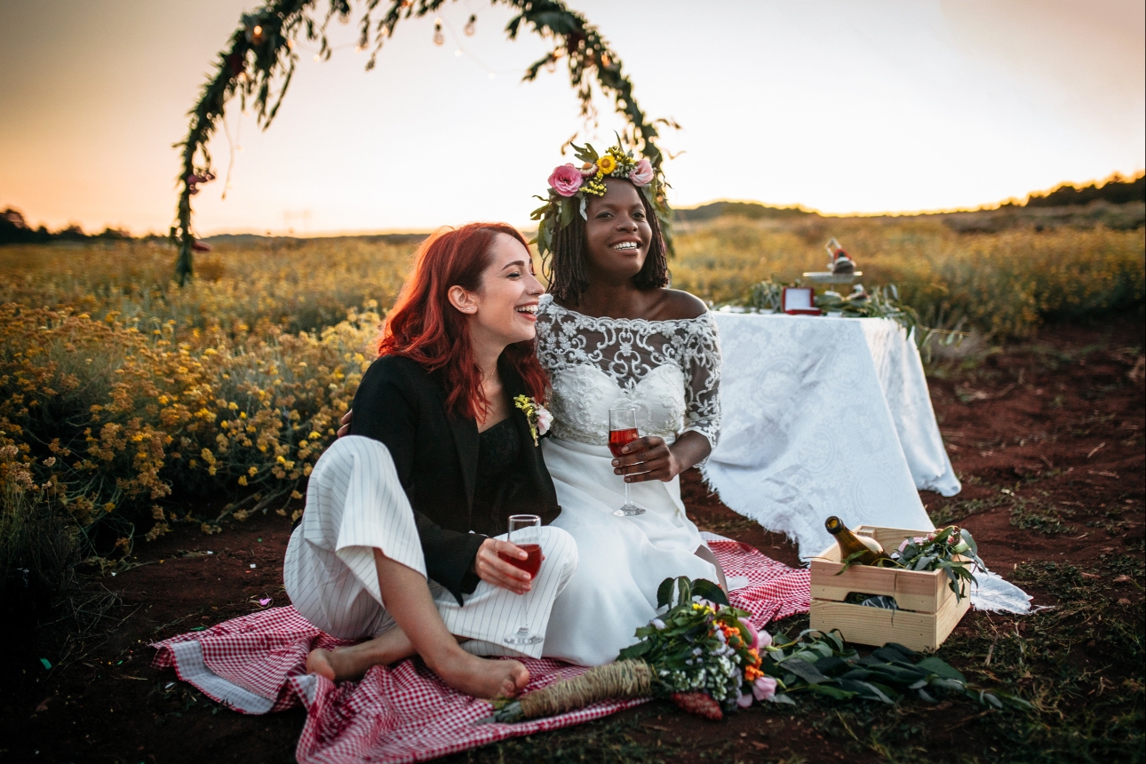 couple sat in. afield after tying the knot with wine glasses