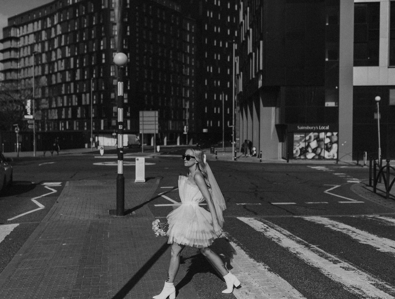 bride with veil and wedding dress holding bouquet outside london building