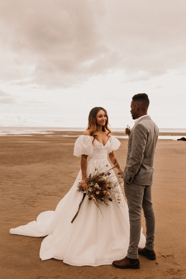 bride and groom standing on a beach