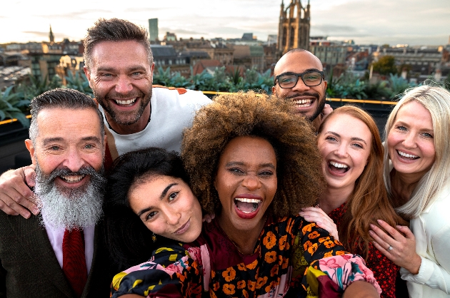 mixed group of men and women taking a self on a hotel roof in a foreign country