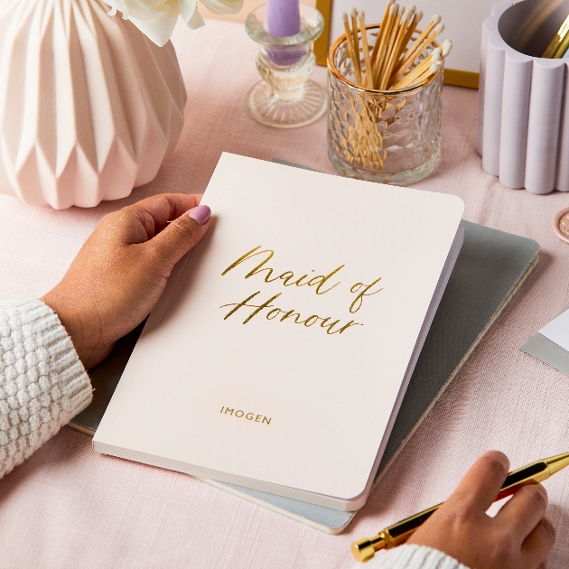 pink note pad with maid of honour written on it in gold and the name imogen