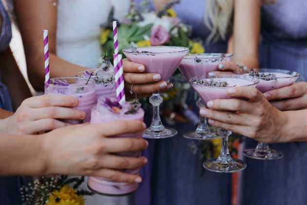 six people holding purple coloured cocktails in martini glasses