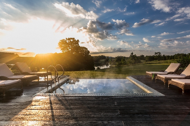 infinity pool at sunset with sunloungers around it