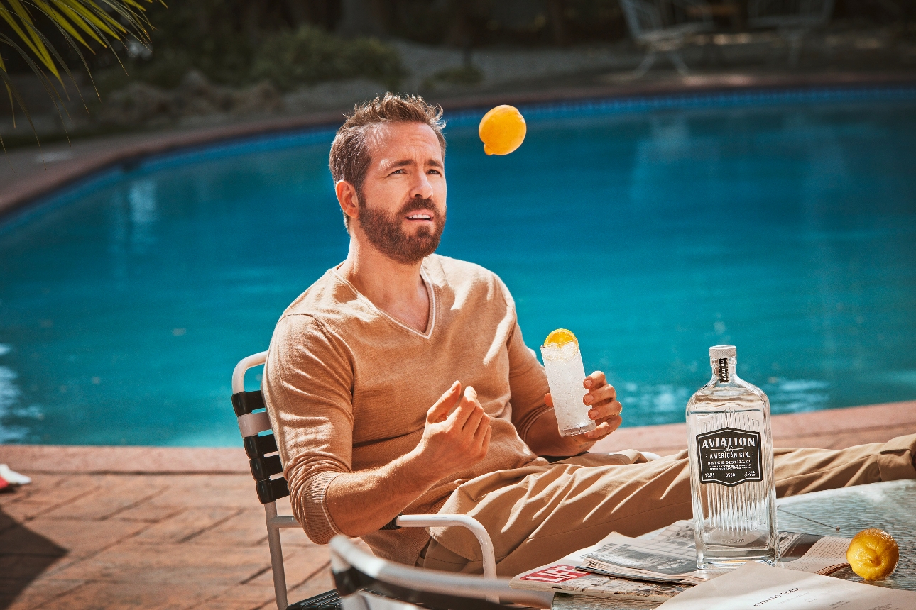 Ryan Reynolds sat by a pool with a cocktail juggling lemons