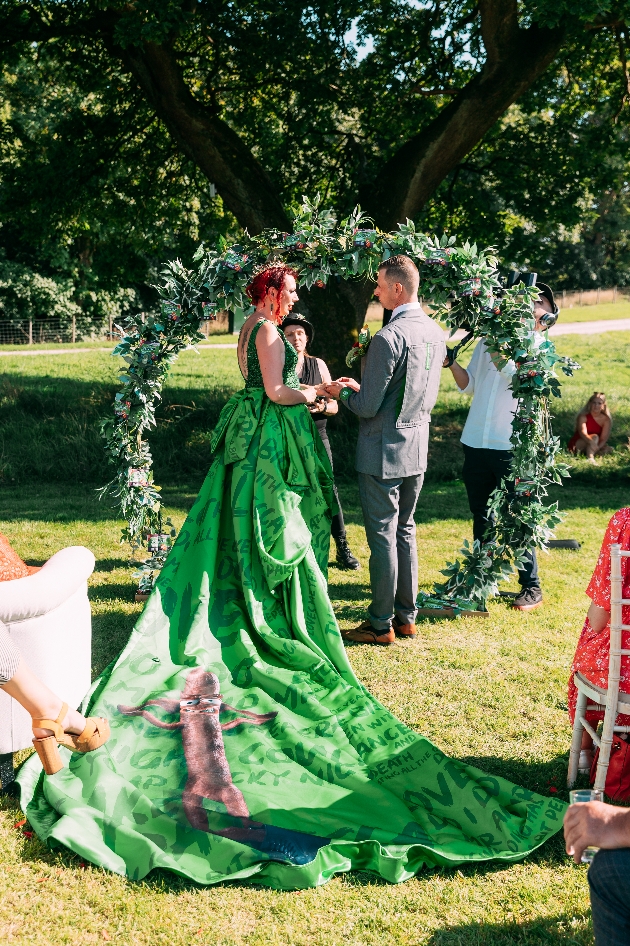 Bride at outside altar wearing Peperami themed green bridal gown