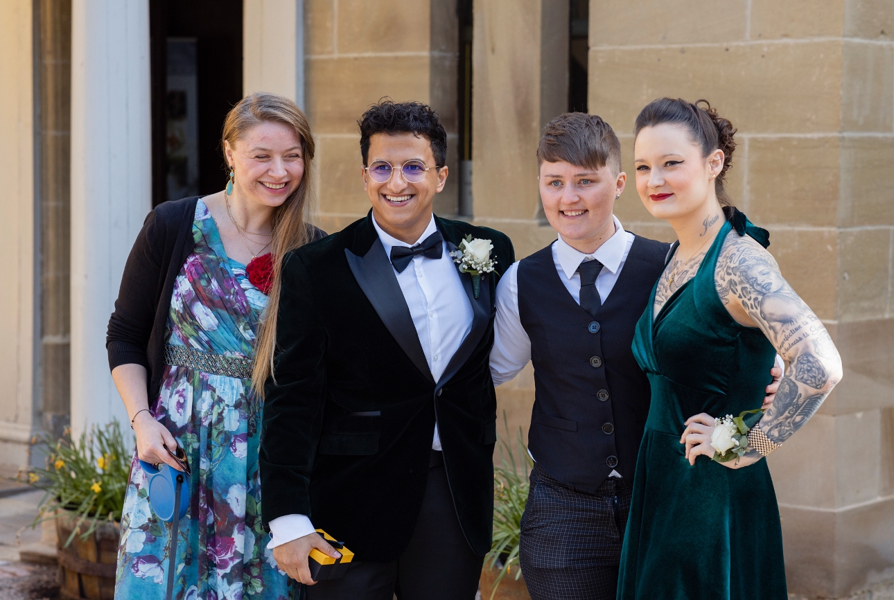 four guests at a wedding posing for an image