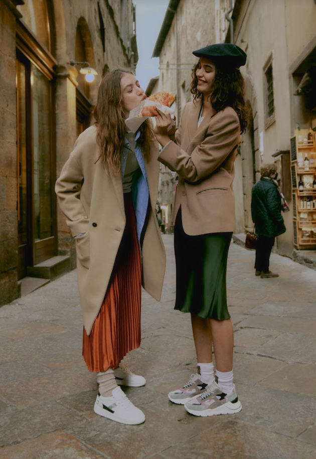 2 women sharing pastry wearing cool sneakers