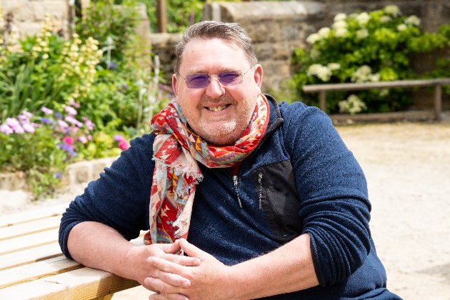 man sat smiling with colourful neck scarf