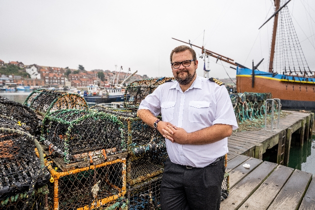 man in fisherman shirt standing in front of boat