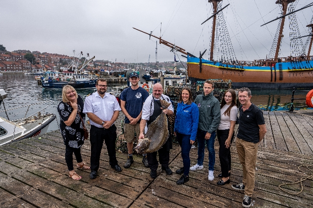 Team standing in front of boat holding fish