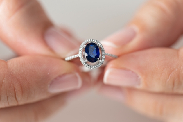Sapphire ring being held between fingers