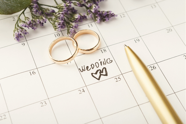 calendar with wedding date written on it with two gold wedding rings