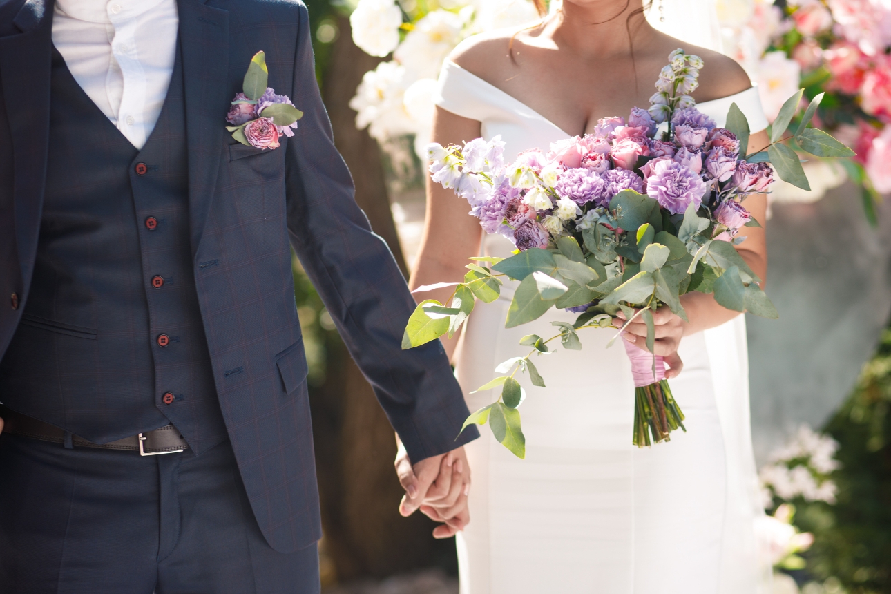 bride and groom holding hand walking along bride also holding bouquet