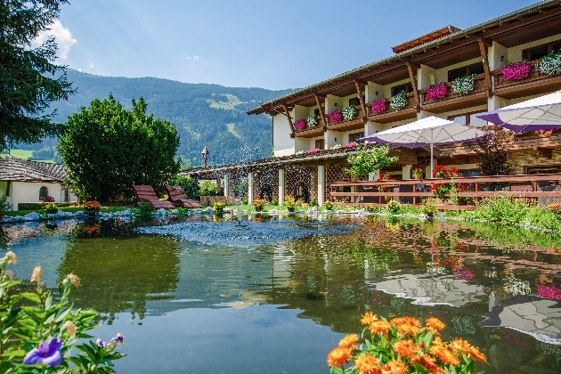 low story hotel in hillside backdrop large pond sunny day