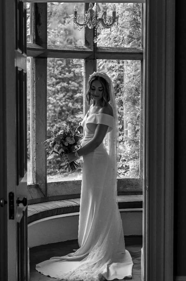 black and white image of bride in front of victorian window