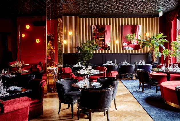 black panel walls with gold wallpaper, lots of mirrors, black velvet chairs, red velvet sofas