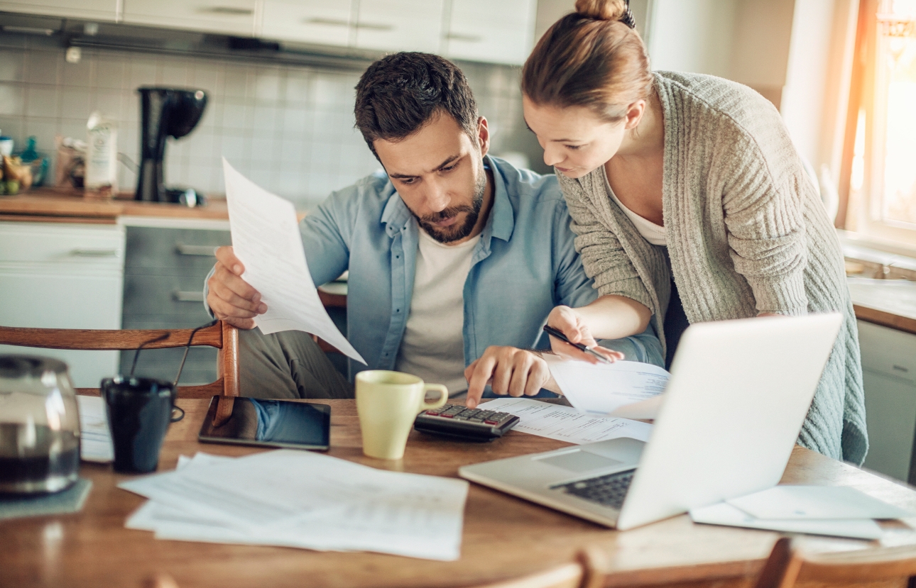 couple with laptop and paperwork on a table looking stressed