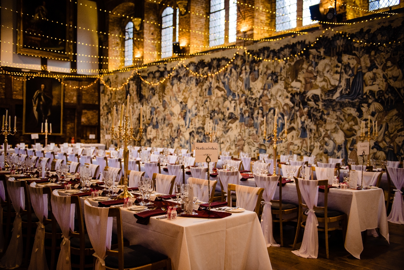 large banqueting room with long tables. Fairylights are draped from ceiling