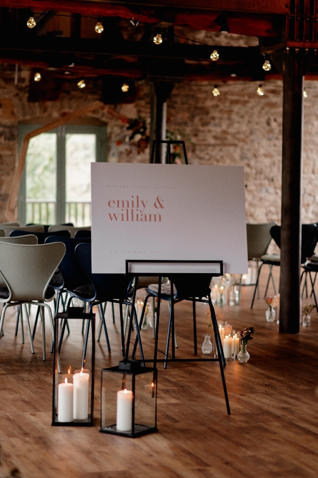 welcome sign on stand in rustic brick room with beams