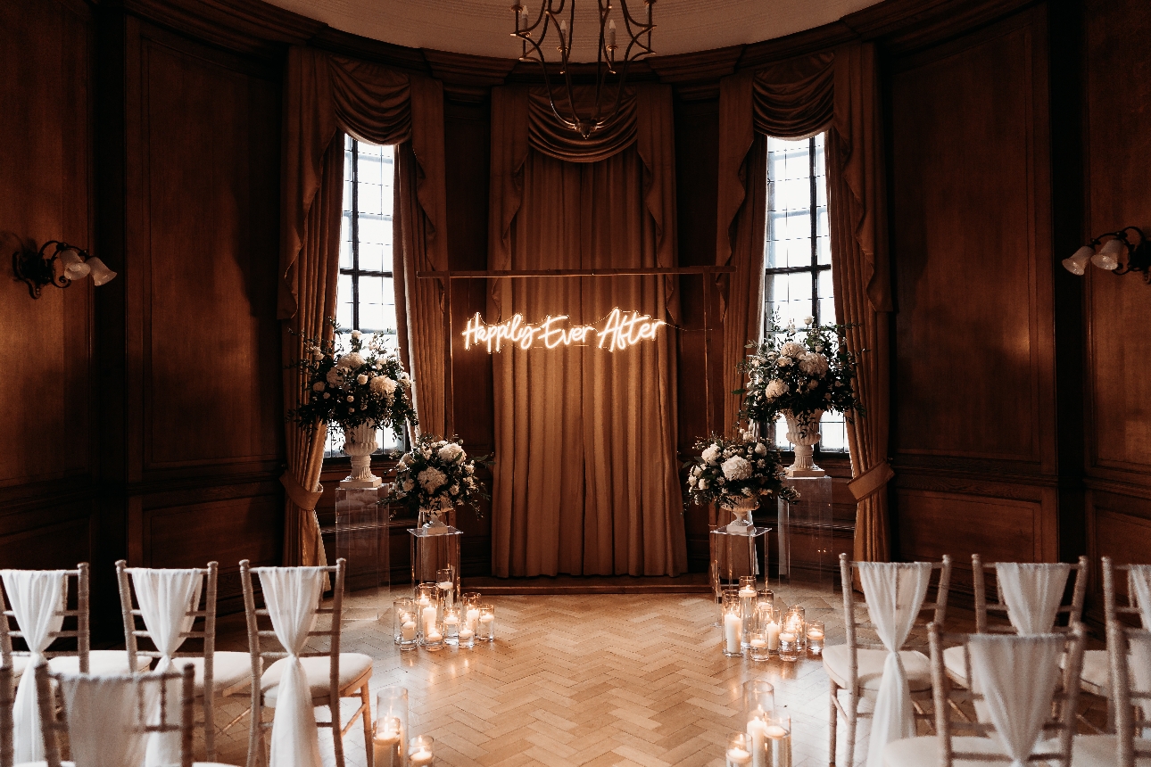 cermeony room parquet floor, chivari chairs, candles, floral displays, light-up sign