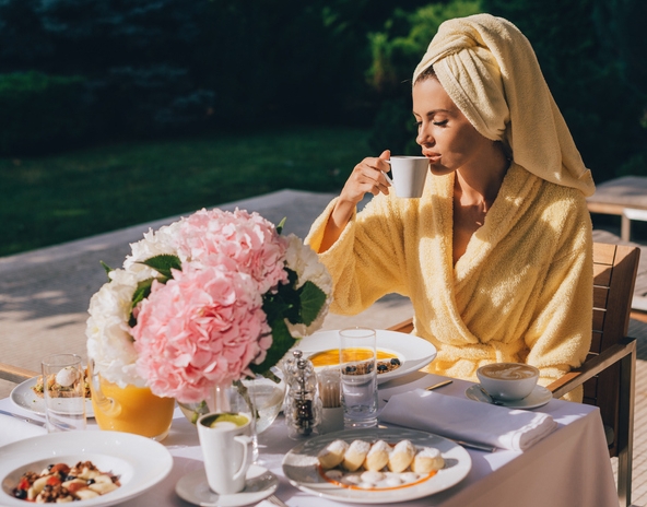 woman eating breakfast outside in the sunshine in a robe