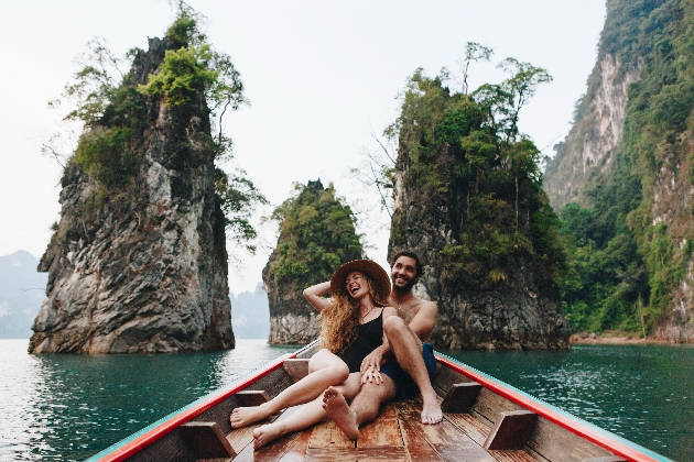 Man and woman sitting in a boat by some mountains