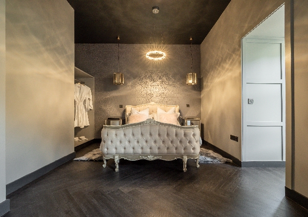 large room in grey and silver with an ornate large bed