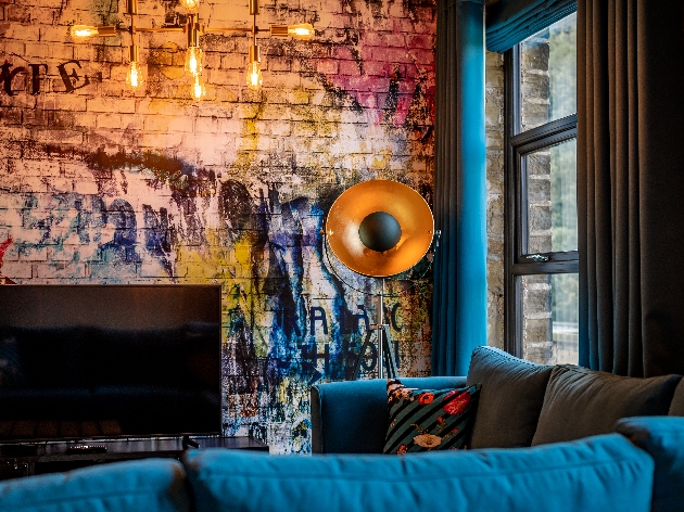 room with brick graffiti walls blue velvet sofa