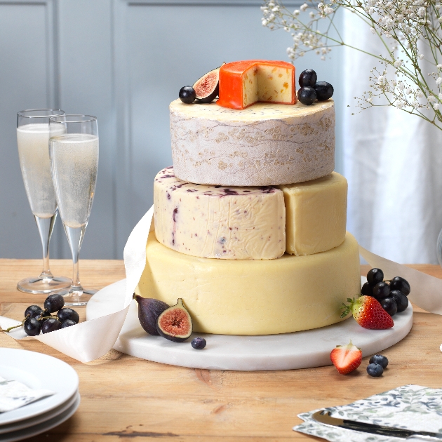 three tiers of different cheese layers making a cake with fruit on it